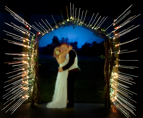 bride and groom kissing under arch