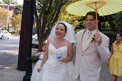 bride and groom walking with yellow paper umbrella