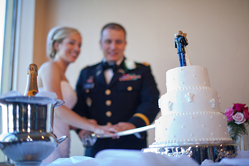 bride and marine groom cutting wedding cake with saber