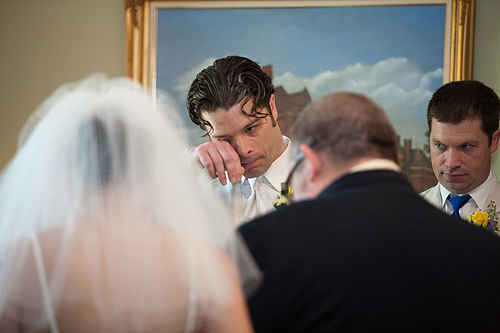 groom wiping tear from eye after seeing bride