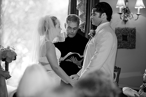 bride and groom in front of officiant holding hands